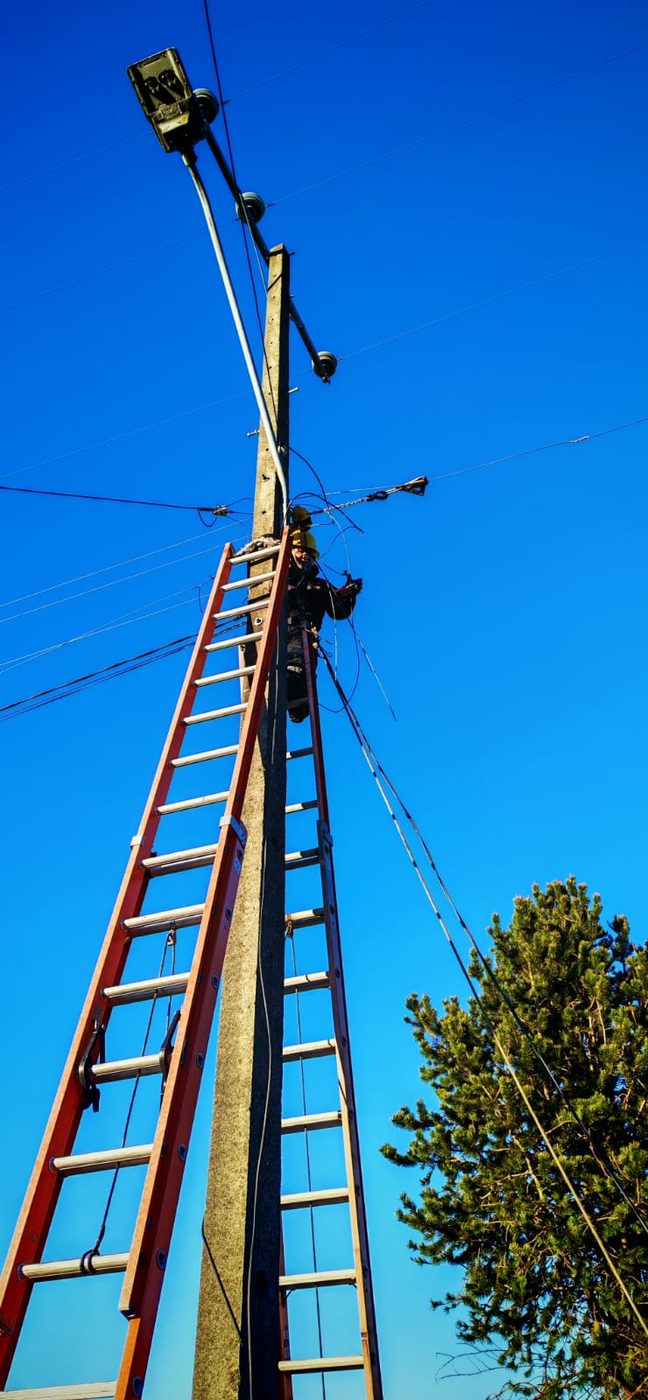 Operario trabajando en altura sobre la línea eléctrica, visto desde la base del poste