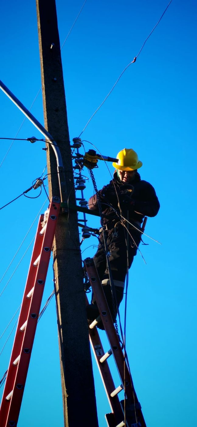Técnico con casco de seguridad trabajando en los aisladores de un poste de media tensión